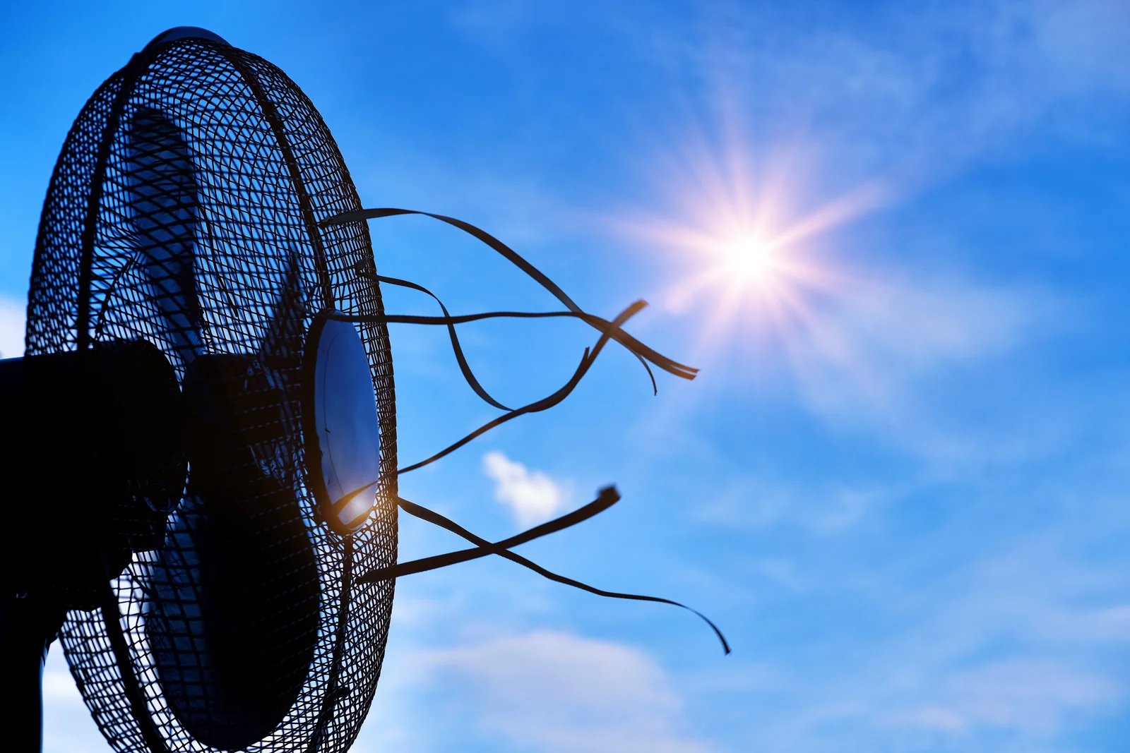 Ein Ventilator mit flatternden Bändern vor tiefblauem Himmel und strahlender Sonne bei großer Hitze.