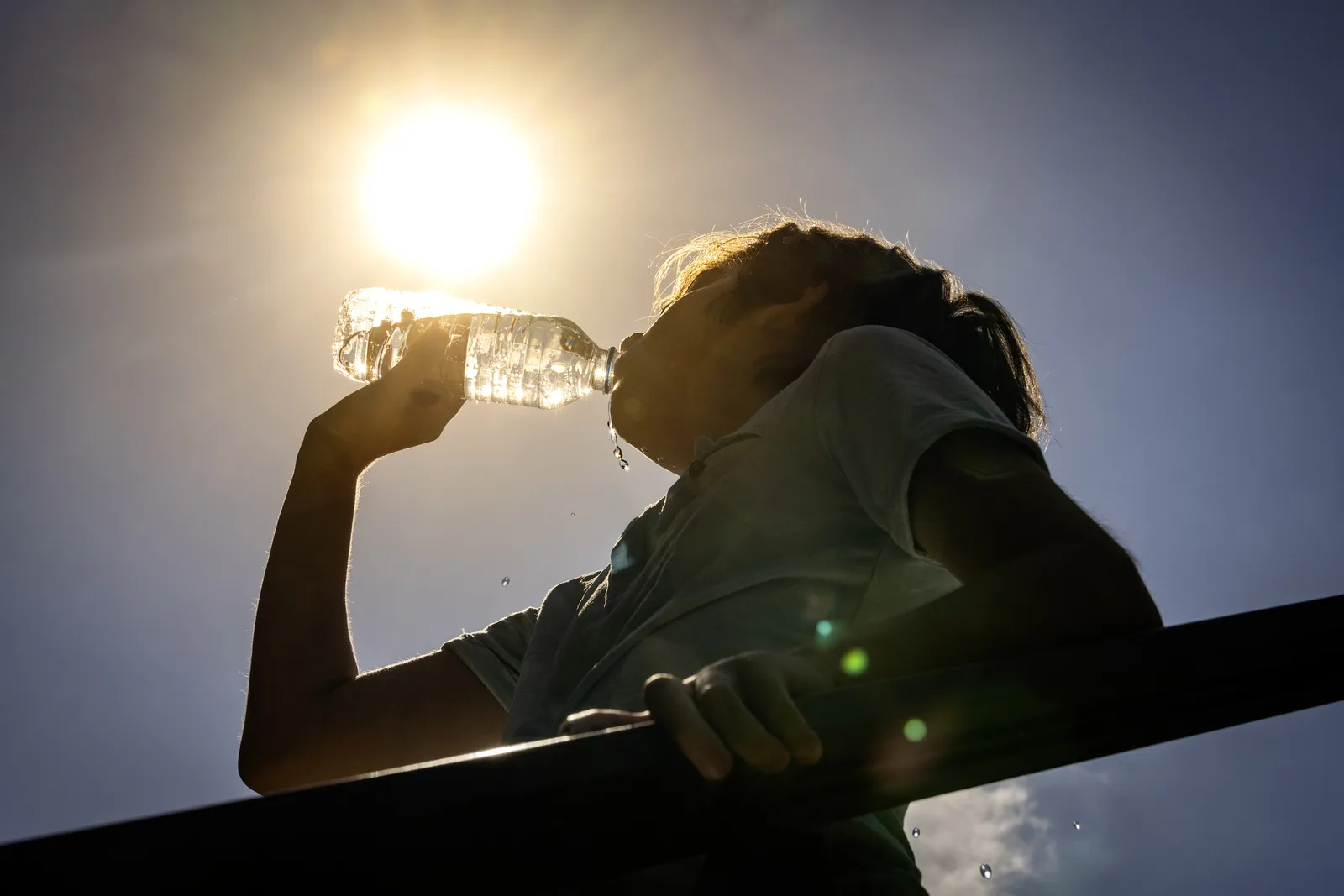 Person trinkt bei gleißender Sonne Wasser aus einer Flasche, Symbolbild für die Hitzewelle in Kärnten und Osttirol