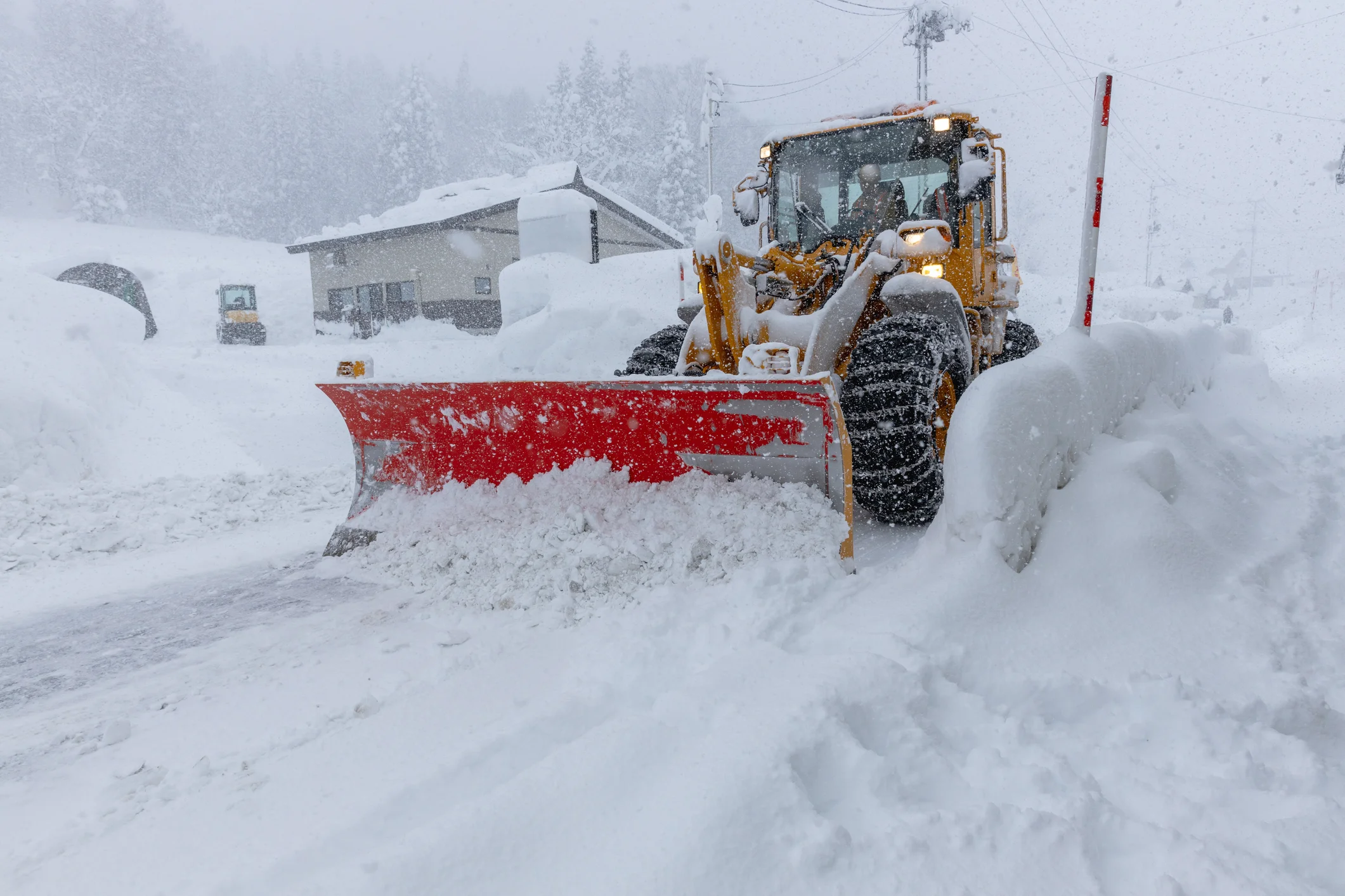 Schneepflug räumt Straße bei starkem Schneefall