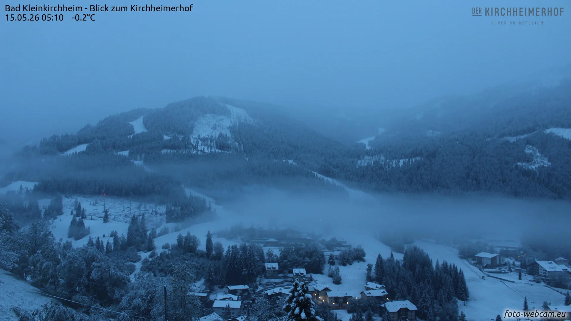 Webcam-Blick zum Kirchheimerhof in Bad Kleinkirchheim am 15. Mai 2026 um 05:10 Uhr: verschneite Landschaft bei minus 0,2 Grad.